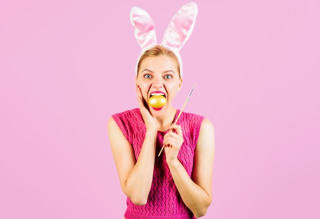 Chica de conejo de pascua en orejas de conejo con huevos de pintura mujer sorprendida con huevo de color y pincel