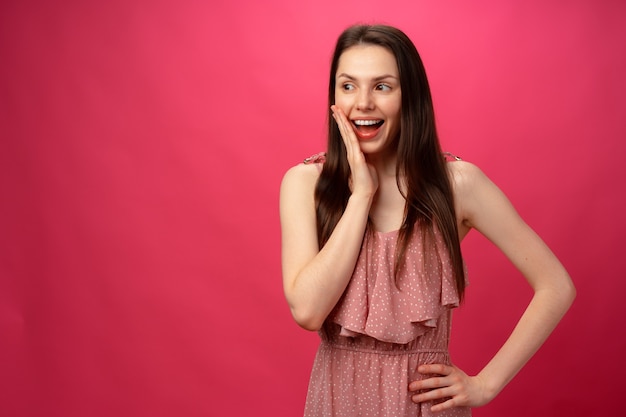 Chica conmocionada y sorprendida gritando contra el fondo rosa