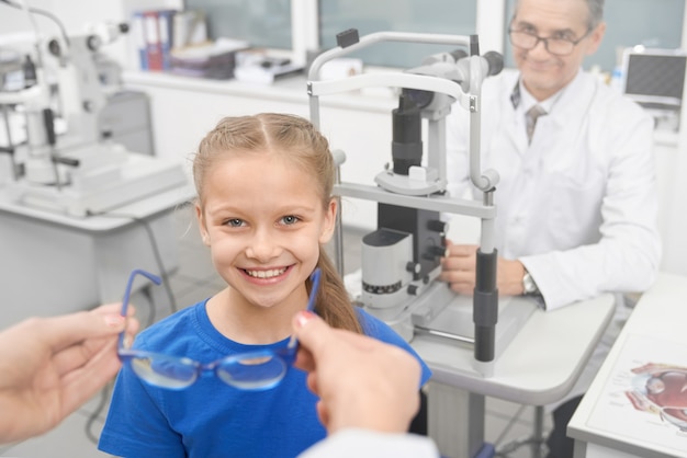 Chica en consulta con optometrista, elegir gafas.