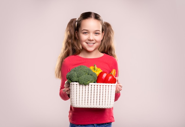 Chica contenta con verduras en la canasta