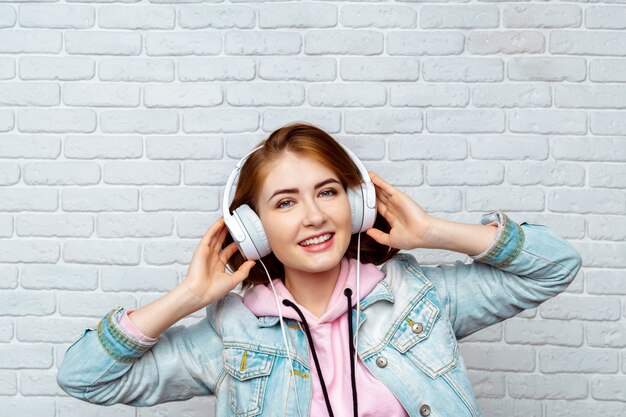 Chica cool de moda bonita escuchando música en auriculares