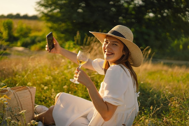 Chica con una copa de champán o vino blanco hace un selfie en la gente del teléfono que usa tecnología