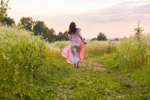 Chica corriendo por el campo con un vestido rosa