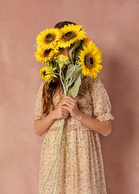 Foto chica cubriendo la cara con girasoles