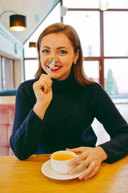 Chica en un cuello alto bebiendo té en un restaurante