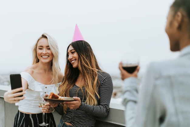 Chica de cumpleaños tomando un selfie con su amiga en una azotea