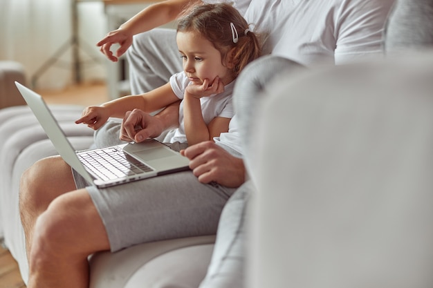 Chica curiosa viendo videos con la familia en la computadora portátil