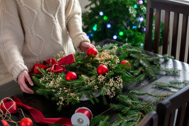 Chica decora la corona de Navidad ella misma en la mesa en casa