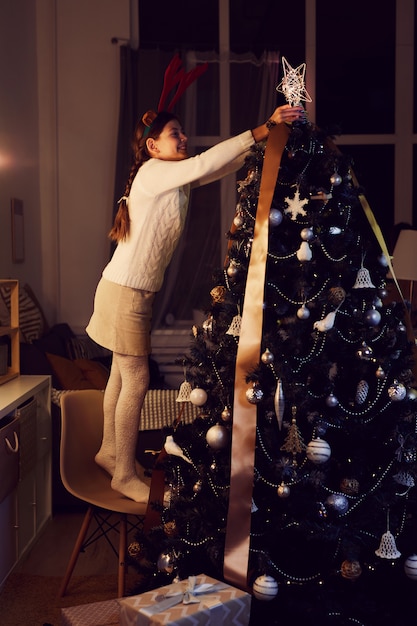 Foto chica decorando árbol de navidad