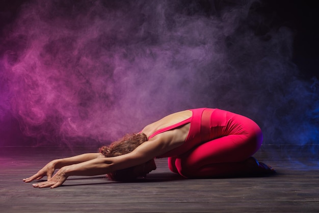 La chica se dedica a estirar sobre un fondo oscuro una elegante foto de fitness y yoga.
