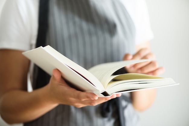 Chica con delantal gris y libro de lectura. Concepto de estilo de vida