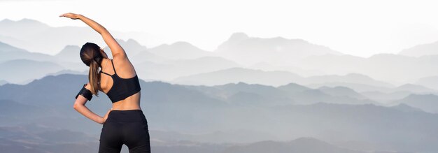 Una chica delgada y atlética se toma un descanso entre clases en el fondo de las montañas temprano en la mañana disfruta del silencio y la libertad