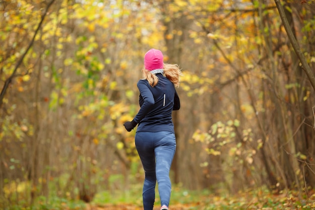 Chica delgada corriendo en el parque en otoño