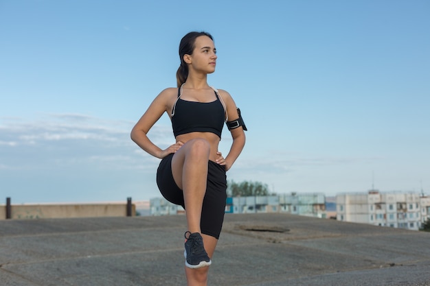 Una chica delgada deportiva en leggings y un top descansando entre ejercicios.