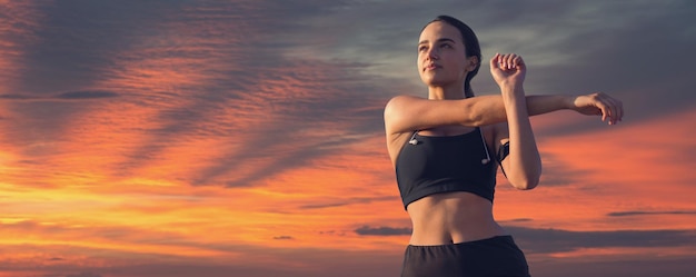 Una chica delgada deportiva en polainas y un top está de pie con una colchoneta de entrenamiento descansando entre ejercicios Hermosas nubes dramáticas atmosféricas