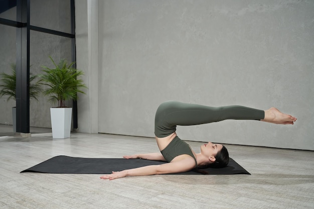 Chica delgada descalza haciendo ejercicio de yoga en el estudio