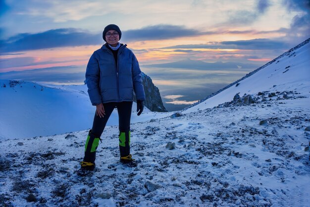 Chica delgada está de pie en la cima de la montaña