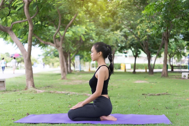 Chica delgada juega yoga en el césped en el parkrelax in nutureAsian Girls les encanta la salud practicando yoga