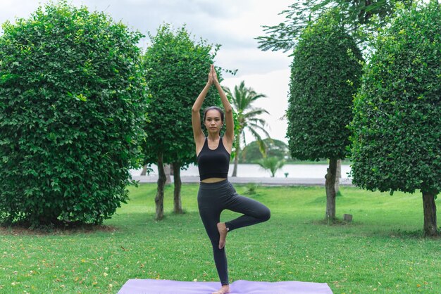 Chica delgada juega yoga en el césped en el parkrelax in nutureAsian Girls les encanta la salud practicando yoga