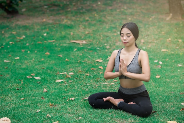 Chica delgada juega yoga en el césped en el parkrelax in nutureAsian Girls les encanta la salud practicando yoga