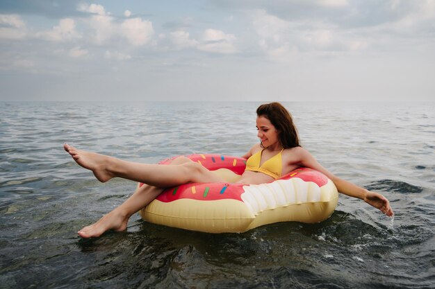 Chica delgada nada en un círculo inflable en el mar en verano