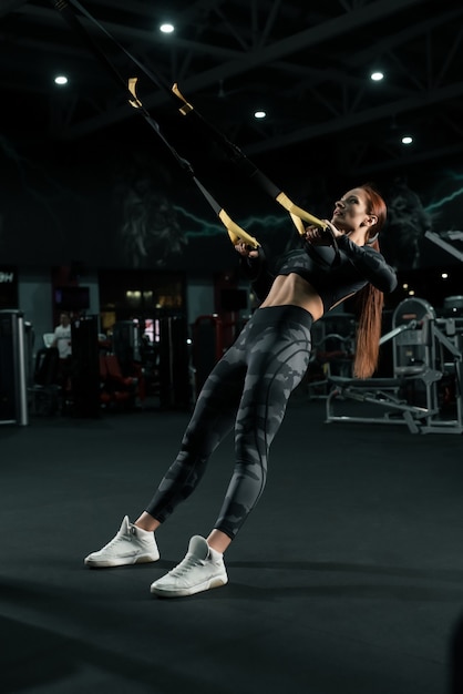 Chica delgada en ropa deportiva haciendo ejercicio en la vista del simulador