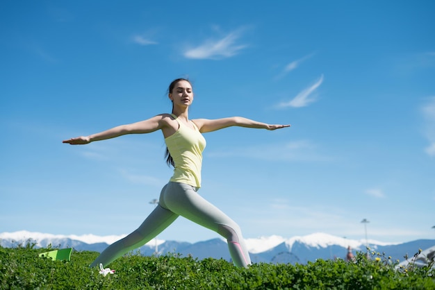 Una chica delgada y tranquila que practica yoga al sol en el parque medita y se relaja