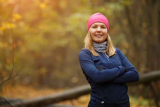 Chica de deporte con sombrero rosa en el bosque de otoño