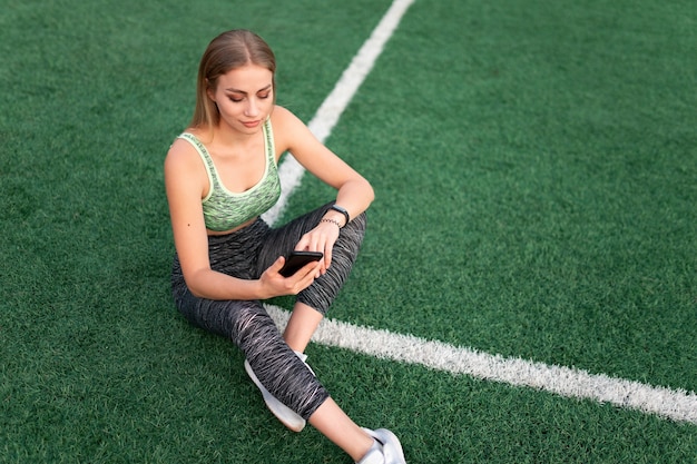 Chica de deportes sentada y usando el teléfono