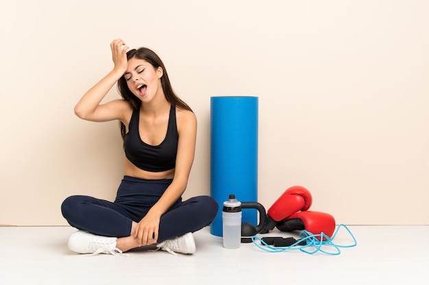 La chica deportiva adolescente sentada en el suelo se ha dado cuenta de algo y tiene la intención de encontrar la solución