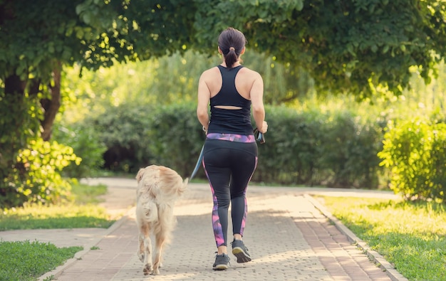 Chica deportiva corriendo con perro golden retriever al aire libre mujer joven trotando con mascota doggy en verano