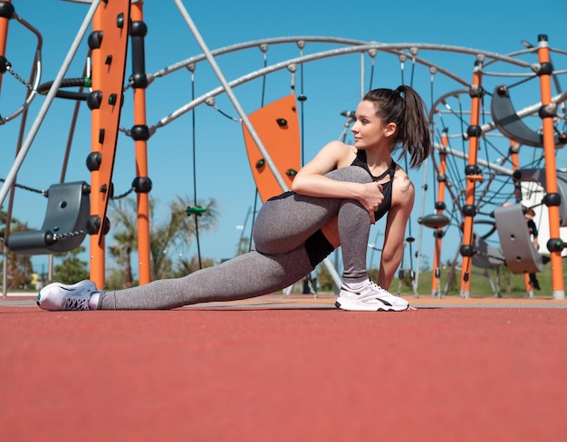 Una chica deportiva hace ejercicio en un campo deportivo al aire libre en verano