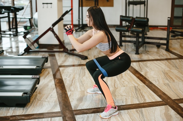 chica deportiva y hermosa chica de pelo largo entrena en el gimnasio