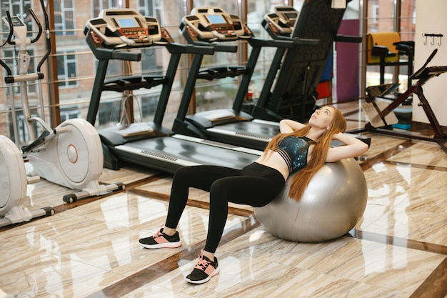 chica deportiva y hermosa chica de pelo largo entrena en el gimnasio