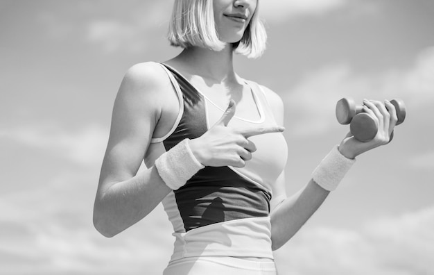 Chica deportiva. Pesa. Ajuste los músculos femeninos que ejercitan. Chica de fitness deportivo. Músculos con mancuerna. En blanco y negro.