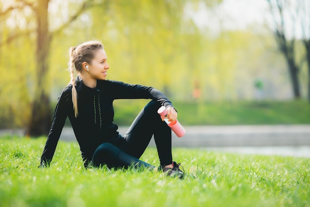 Chica deportiva relajándose en el césped del parque