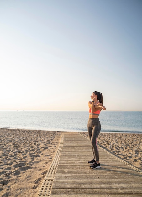 Chica deportiva saludable haciendo ejercicio de estiramiento temprano en la mañana en la playa