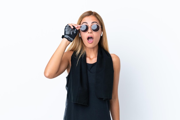 Chica deportiva uruguaya rubia aislada de fondo blanco con gafas y sorprendida