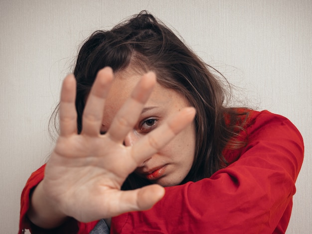 Foto chica deprimida en una camisa roja contra la pared