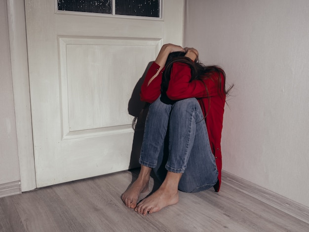 Foto chica deprimida en una camisa roja contra la pared