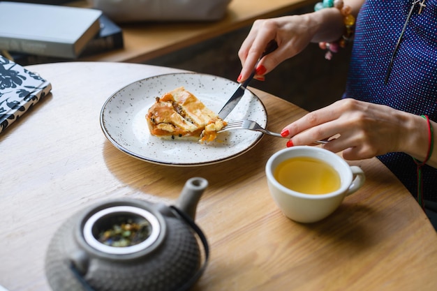 La chica desayuna en una cafetería, come un pastel y bebe té.