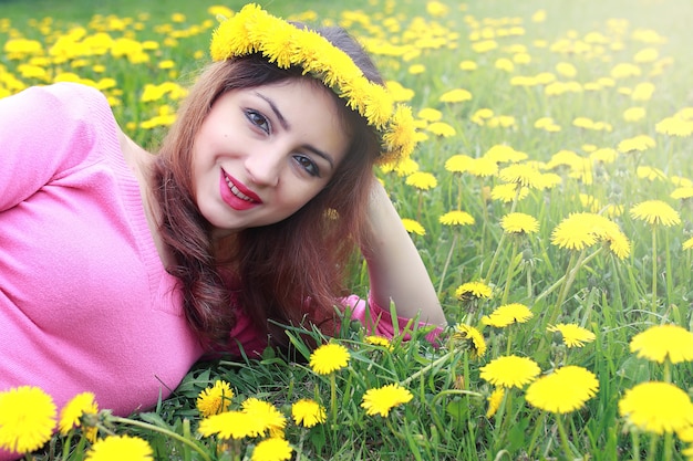 Chica descansando en un día soleado en una pradera de dientes de león amarillos