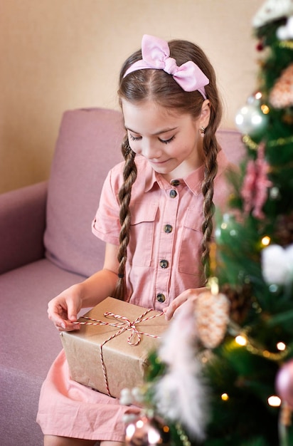 chica desempaca un regalo de Navidad en el fondo del árbol de Navidad