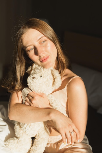 La chica se despierta por la mañana se estira en la cama y el sol brilla desde la ventana mujer joven feliz