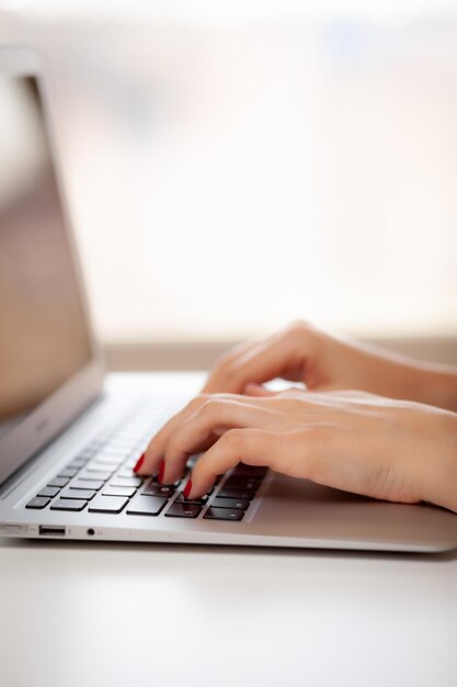 La chica detrás de la computadora portátil. Manos femeninas escribiendo texto en el teclado mientras intercambian mensajes