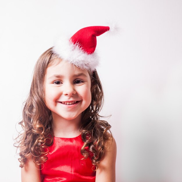 Chica con diadema de gorro de Papá Noel sobre pared blanca, espacio de copia