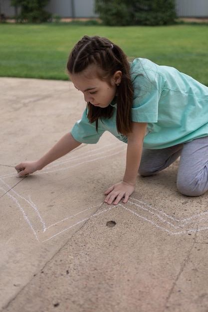 Chica dibuja con crayones de colores en el pavimento Dibujos de niños con tiza en la pared Niño creativo Alegría de la infancia