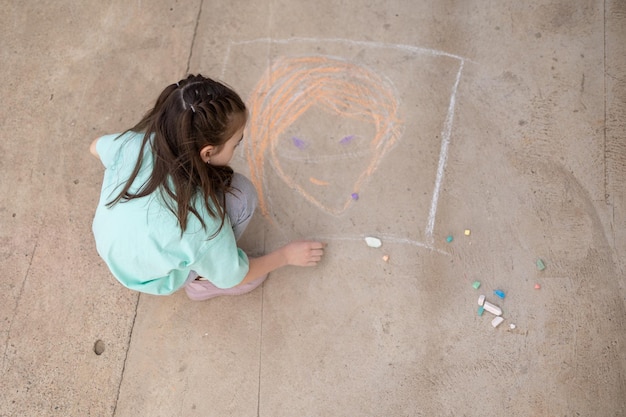 Chica dibuja con crayones de colores en el pavimento Dibujos de niños con tiza en la pared Niño creativo Alegría de la infancia