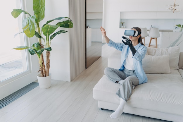 Foto chica discapacitada con brazo cibernético en gafas vr en casa tecnología para recuperación y rehabilitación