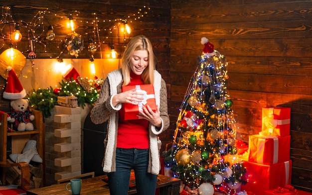 Chica disfruta de un ambiente cálido y acogedor la víspera de Navidad. Momentos agradables. Alegría navideña. Luces de guirnalda de adornos navideños interiores de madera de mujer. Árbol de Navidad. Lleno de alegría, alegría y amor.